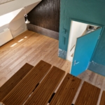 Blick auf den Dielenboden vor der Reinigung; die Wände und die Möbel sind schon mit Folien abgedeckt