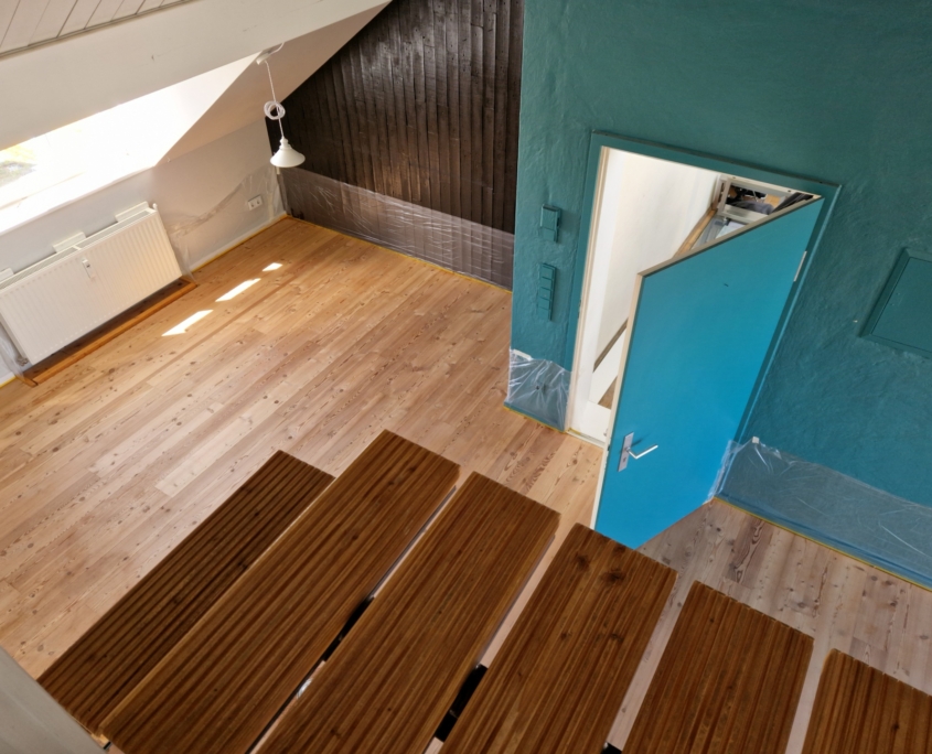 Blick auf den Dielenboden vor der Reinigung; die Wände und die Möbel sind schon mit Folien abgedeckt